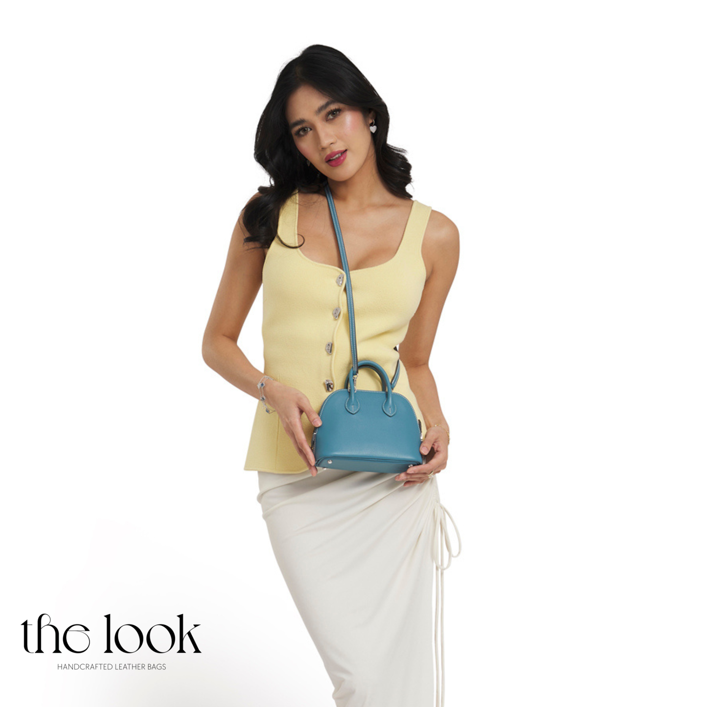 Woman holding a blue handbag (Beaumont Mini) against a white background with 'the look' branding.