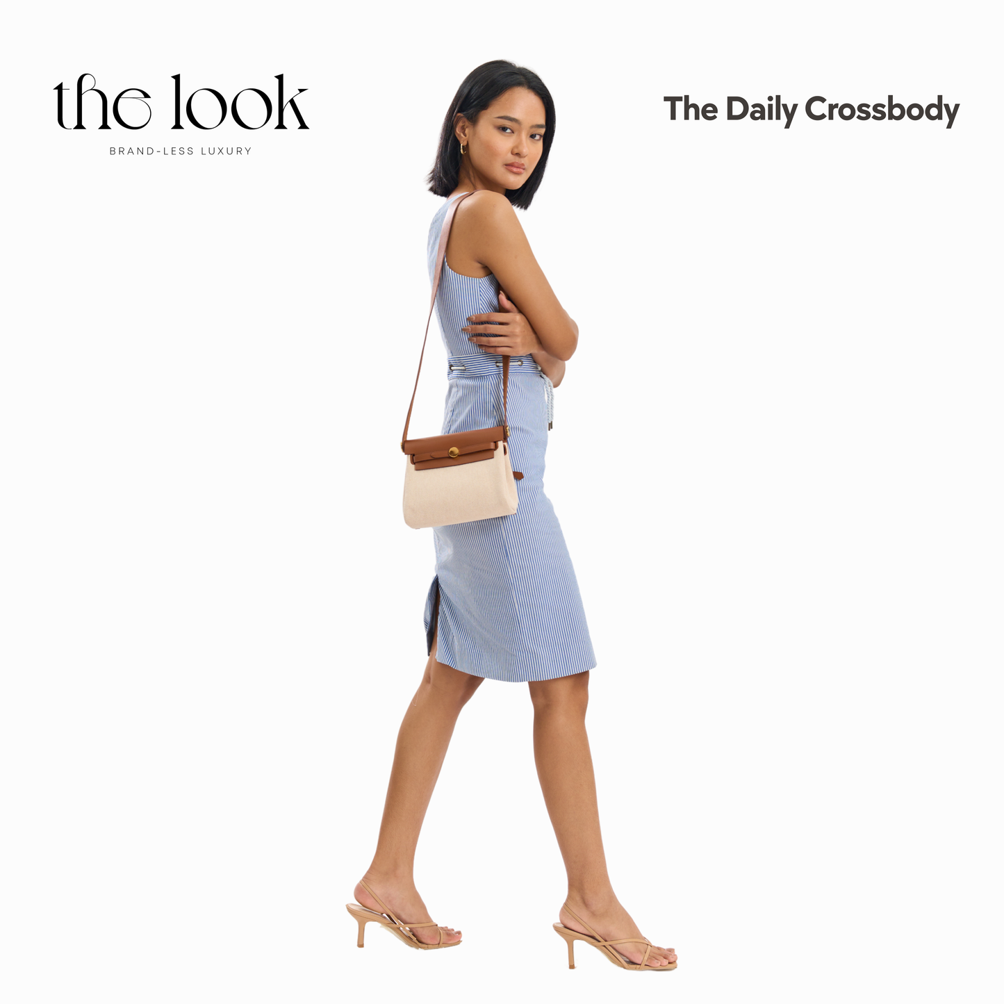 Woman in a light blue dress holding a beige crossbody bag with 'the look' branding. | The Look Officiel