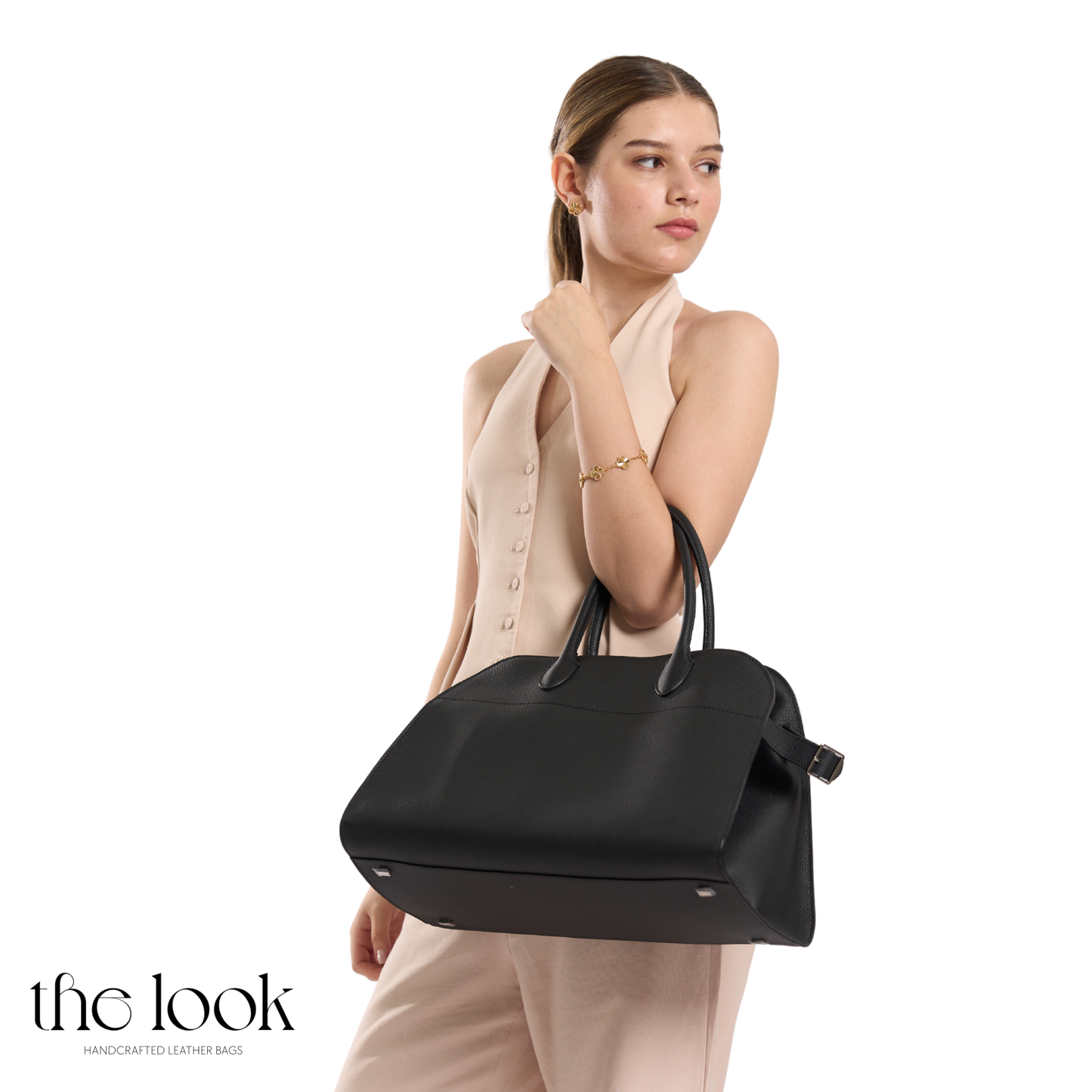 Woman holding a black handbag against a white background | The Look Officiel