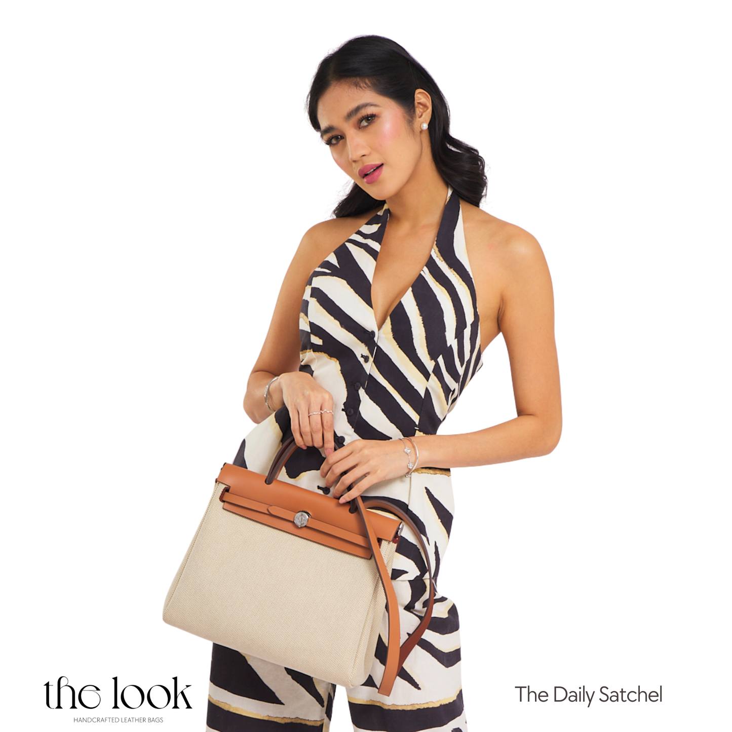 Woman holding a beige handbag with a zebra-patterned outfit, featuring 'The Daily Satchel' brand. | The Look Officiel