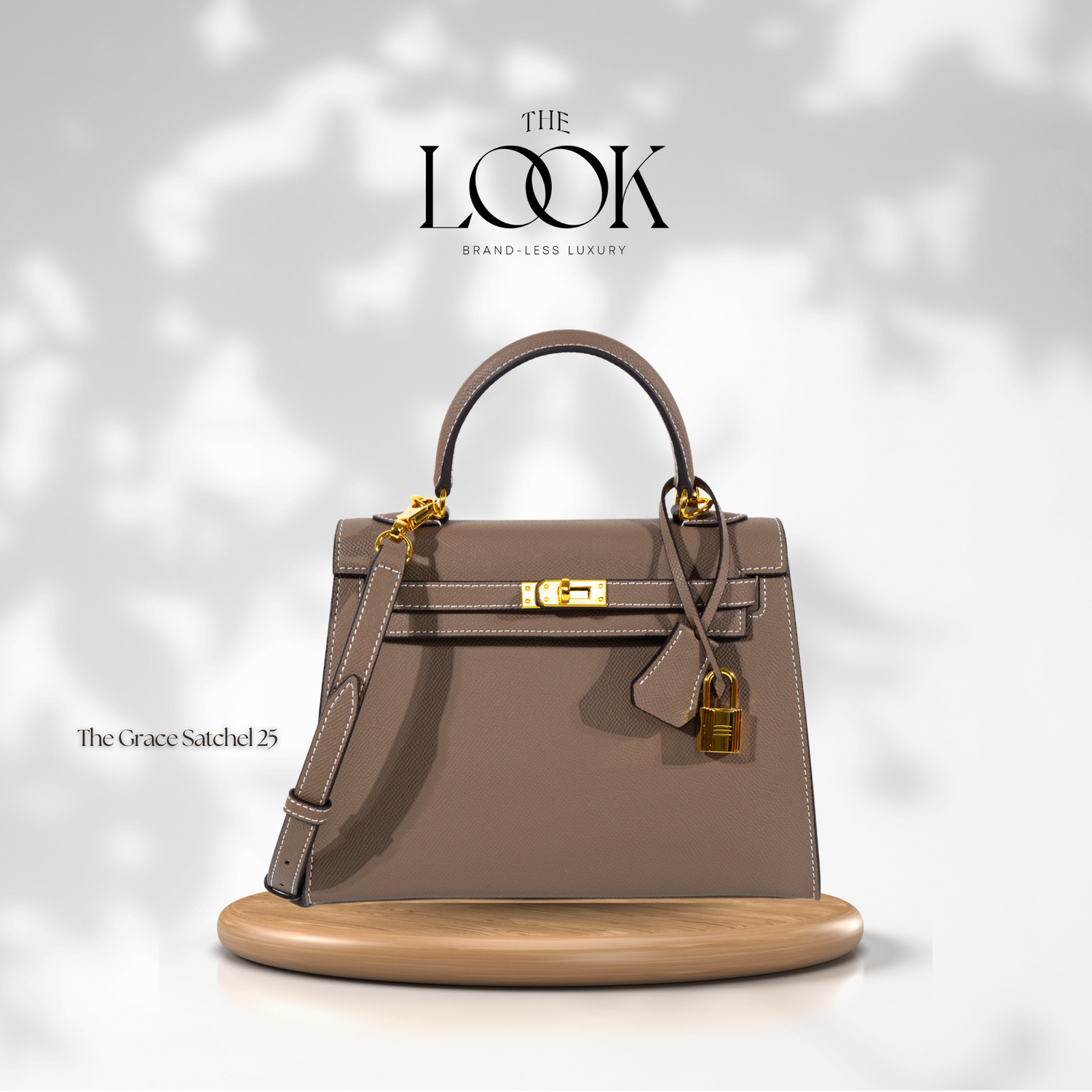 The Grace 25 satchel Epsom leather handbag with gold hardware, displayed on a wooden platform, against a white background with the logo 'The Look' at the top. | The Look Officiel