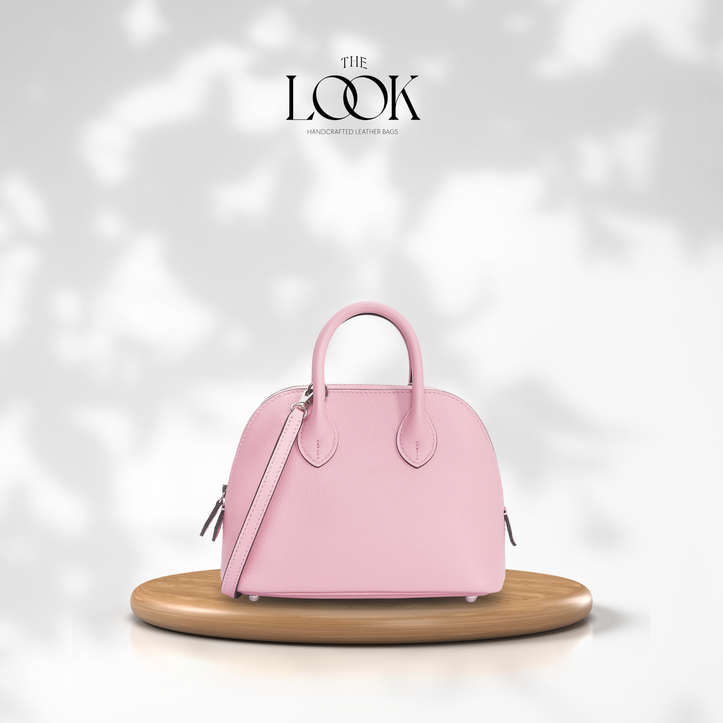 Pink handbag on a wooden stand with a soft white background and 'The Look' brand logo.| The Look Officiel