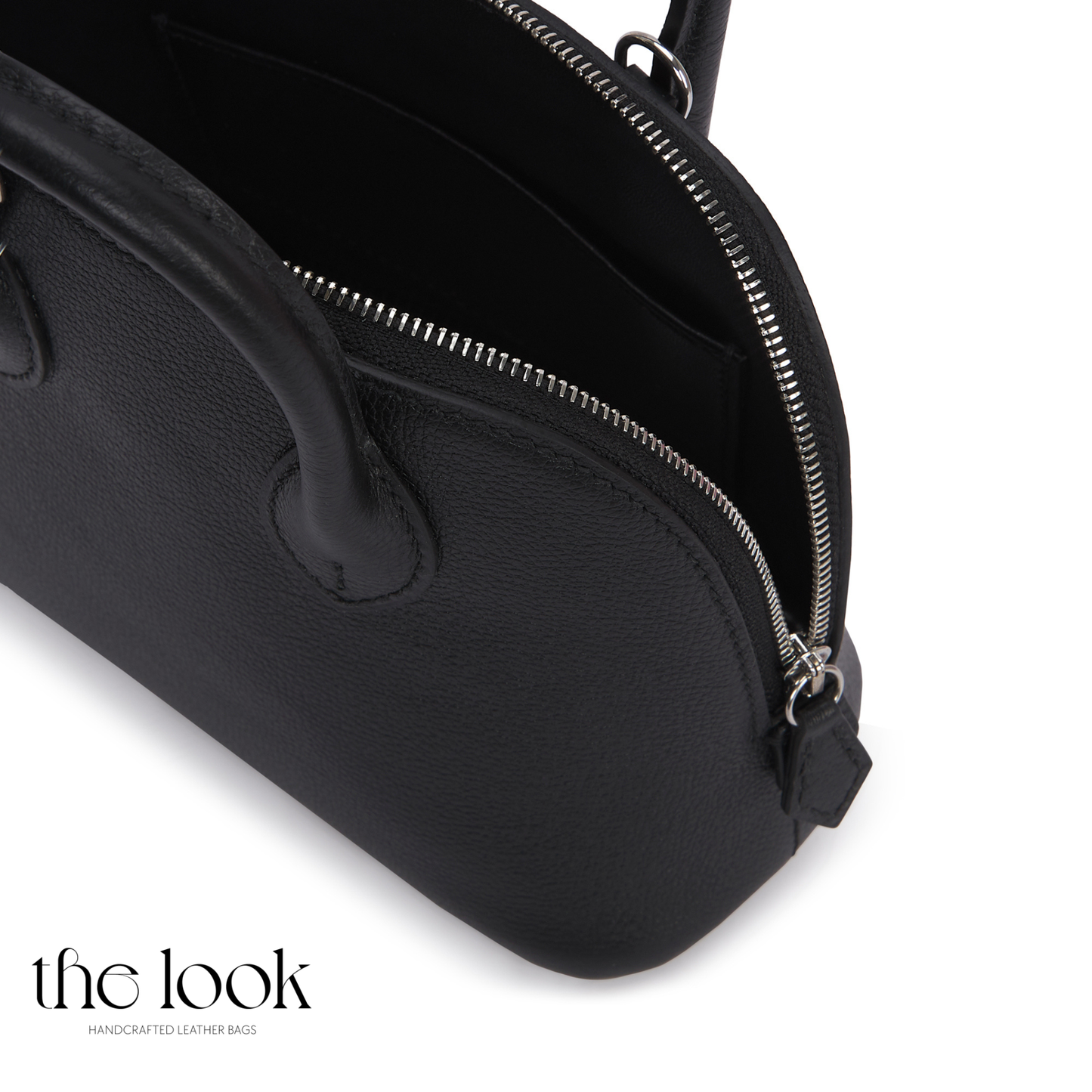 Black handbag with a zipper on a white background, featuring 'the look' brand. | The Look Officiel