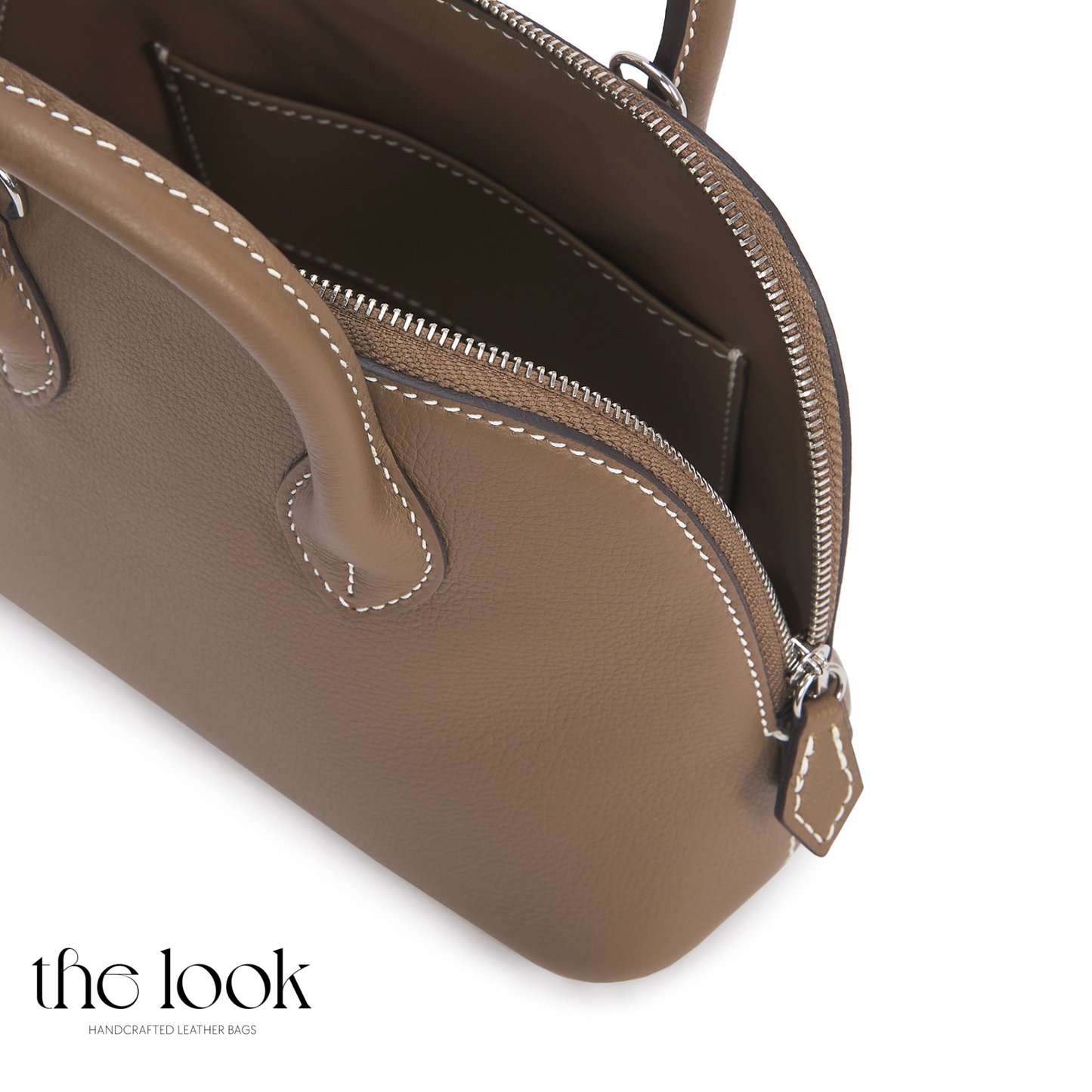 Brown leather handbag with visible stitching on a white background, featuring 'the look' brand. | The Look Officiel