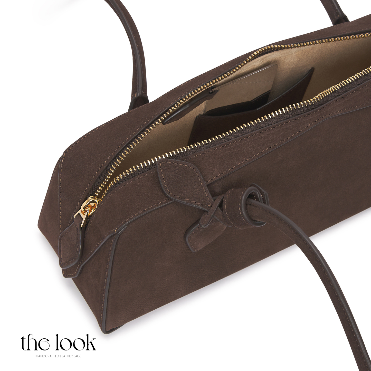 Brown leather handbag with a gold zipper on a white background, featuring 'the look' brand. | The Look Officiel
