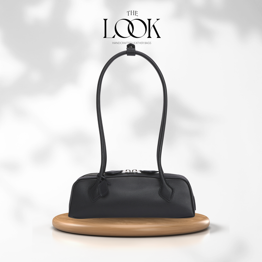 Black handbag on a wooden stand with 'The Look' brand logo above on a light gray background | The Look Officiel