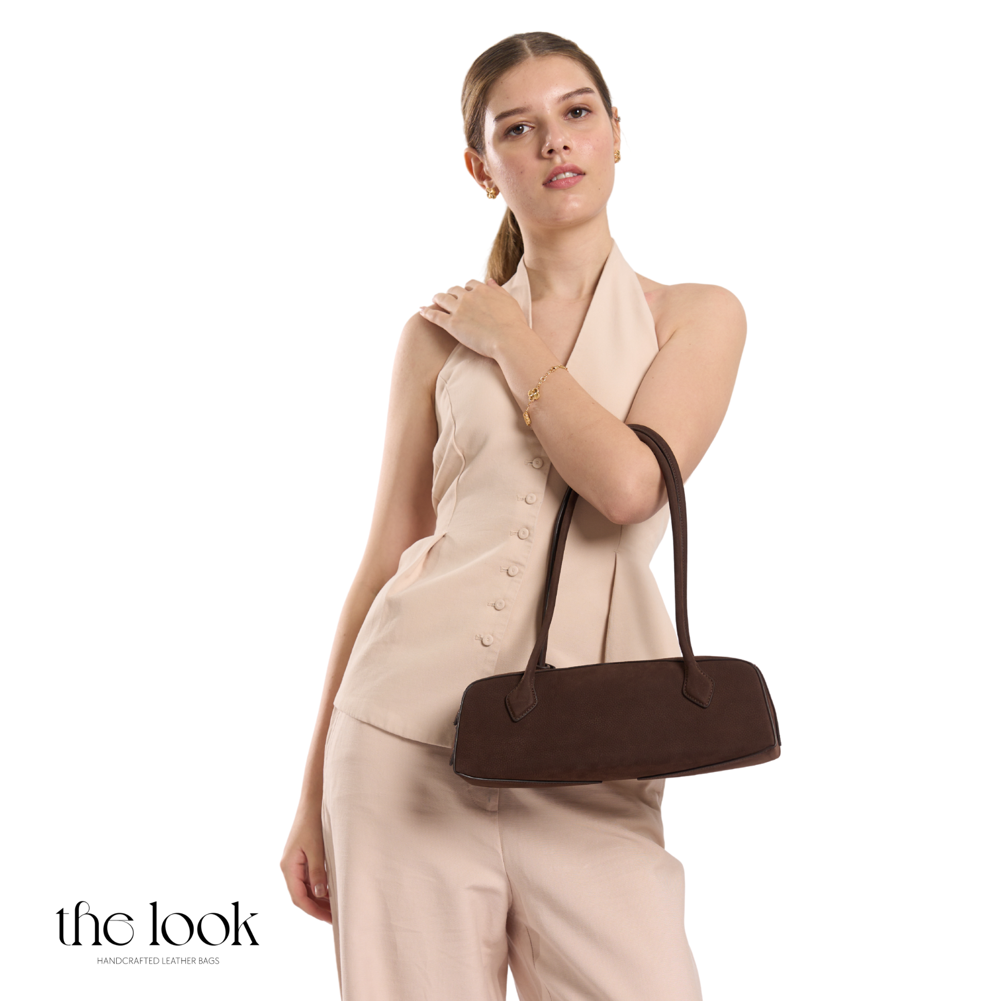 Woman holding a brown handbag against a white background | The Look Officiel