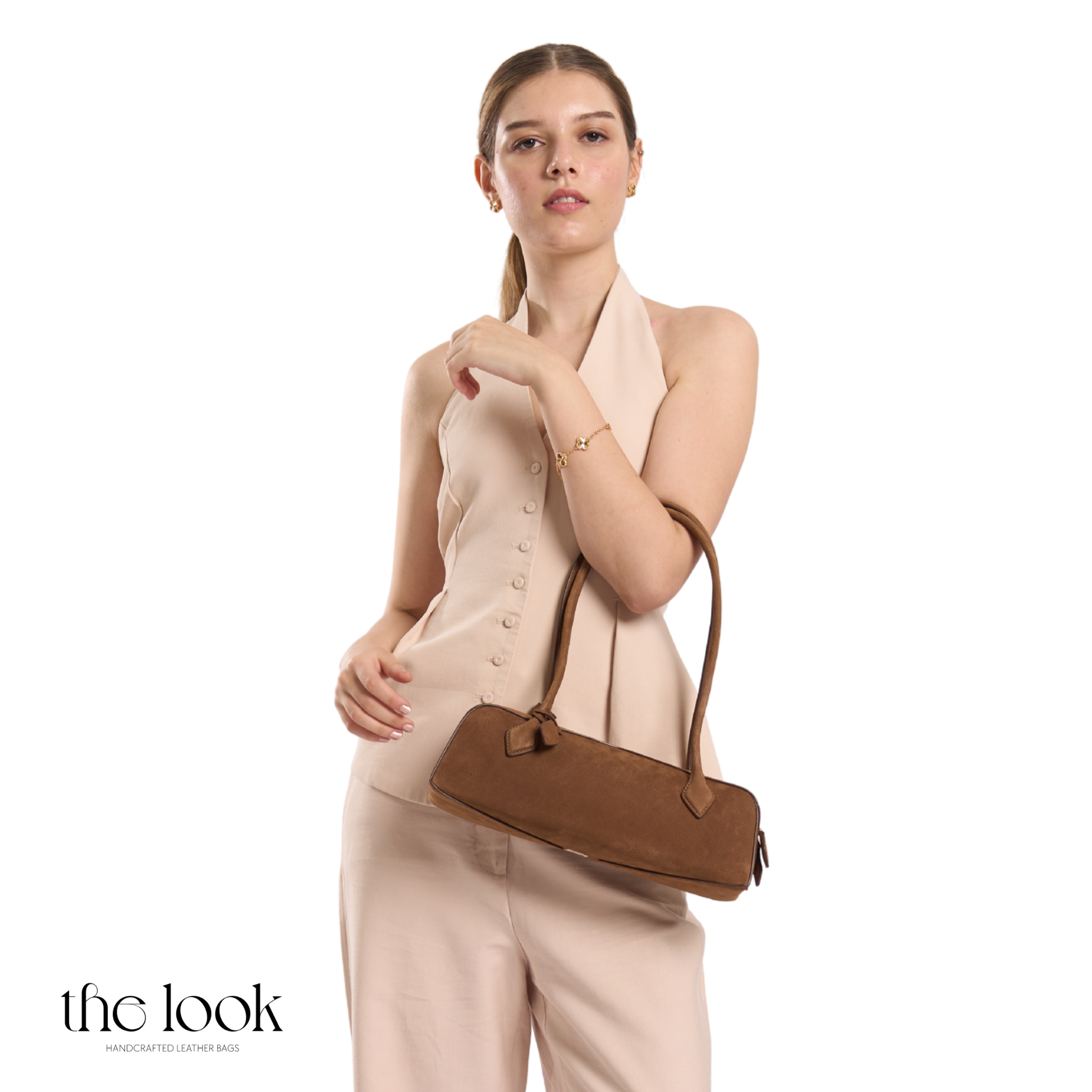Woman holding a brown handbag against a white background with 'the look' branding. | The Look Officiel