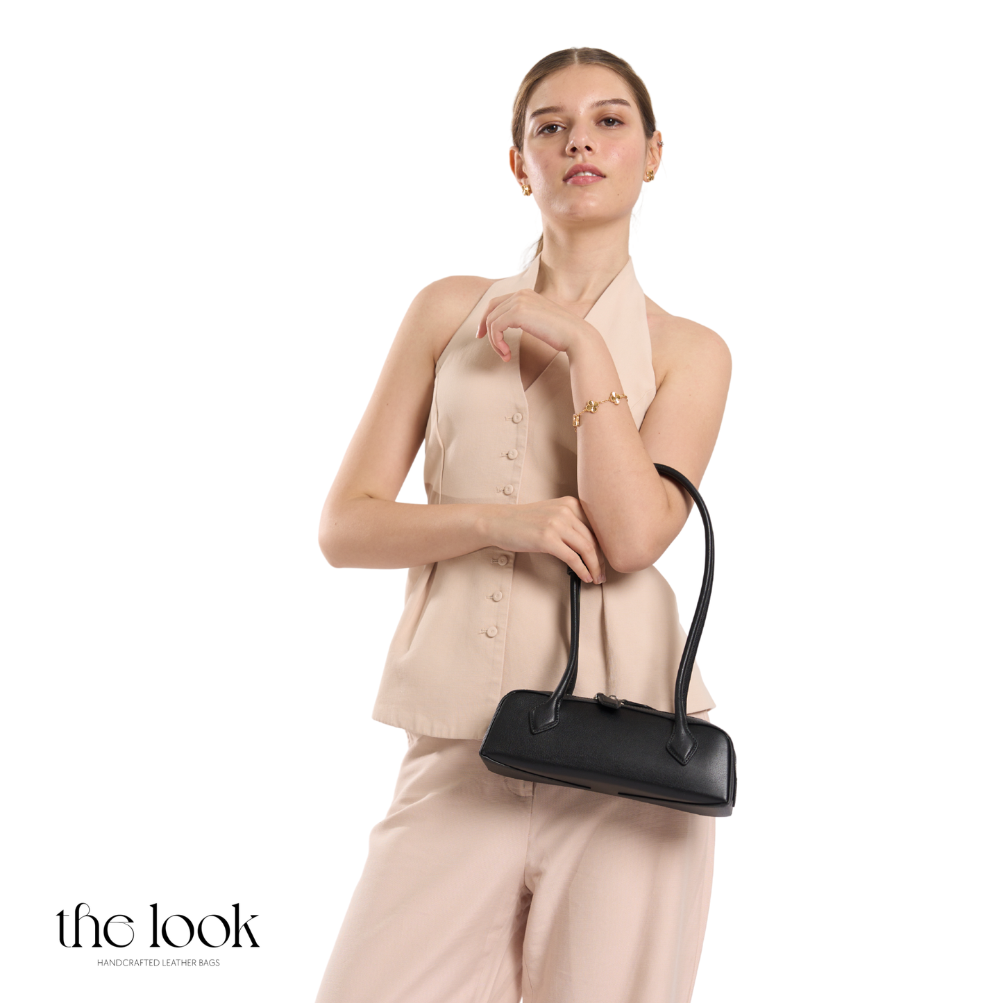 Woman holding a black handbag against a white background | The Look Officiel