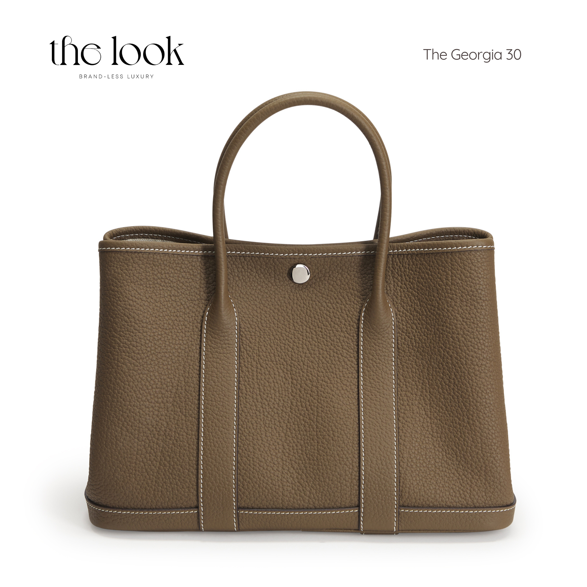 Brown leather tote bag with a silver button on a white background, featuring 'the look' branding. | The Look Officiel