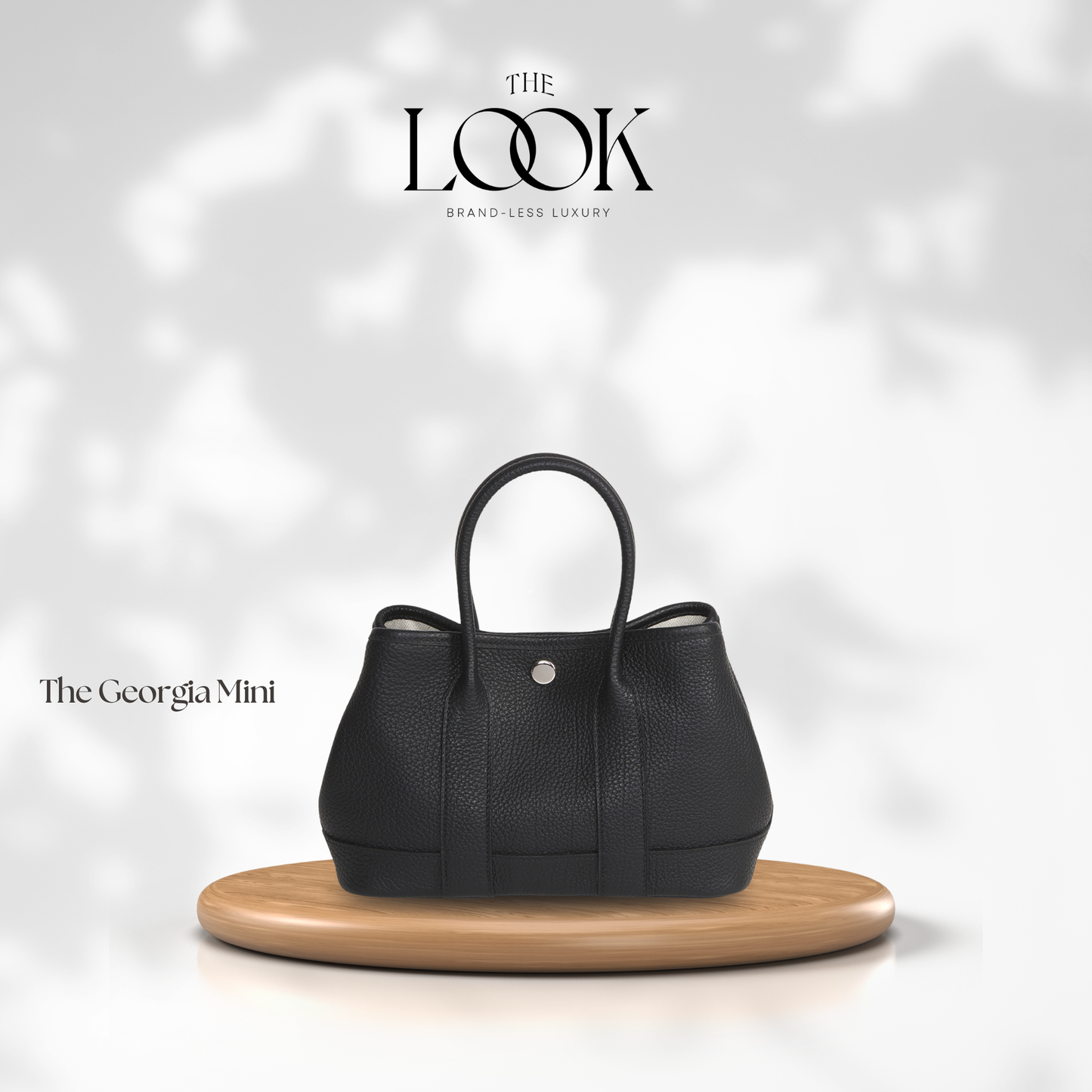 Black handbag on a wooden stand with 'The Look' branding on a light background | The Look Officiel