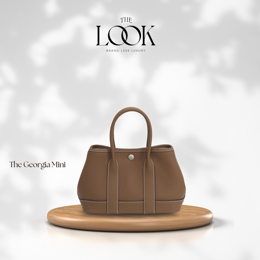 The Georgia Mini Tote in Etoupe Pebbled Calfskin Leather displayed on wooden stand