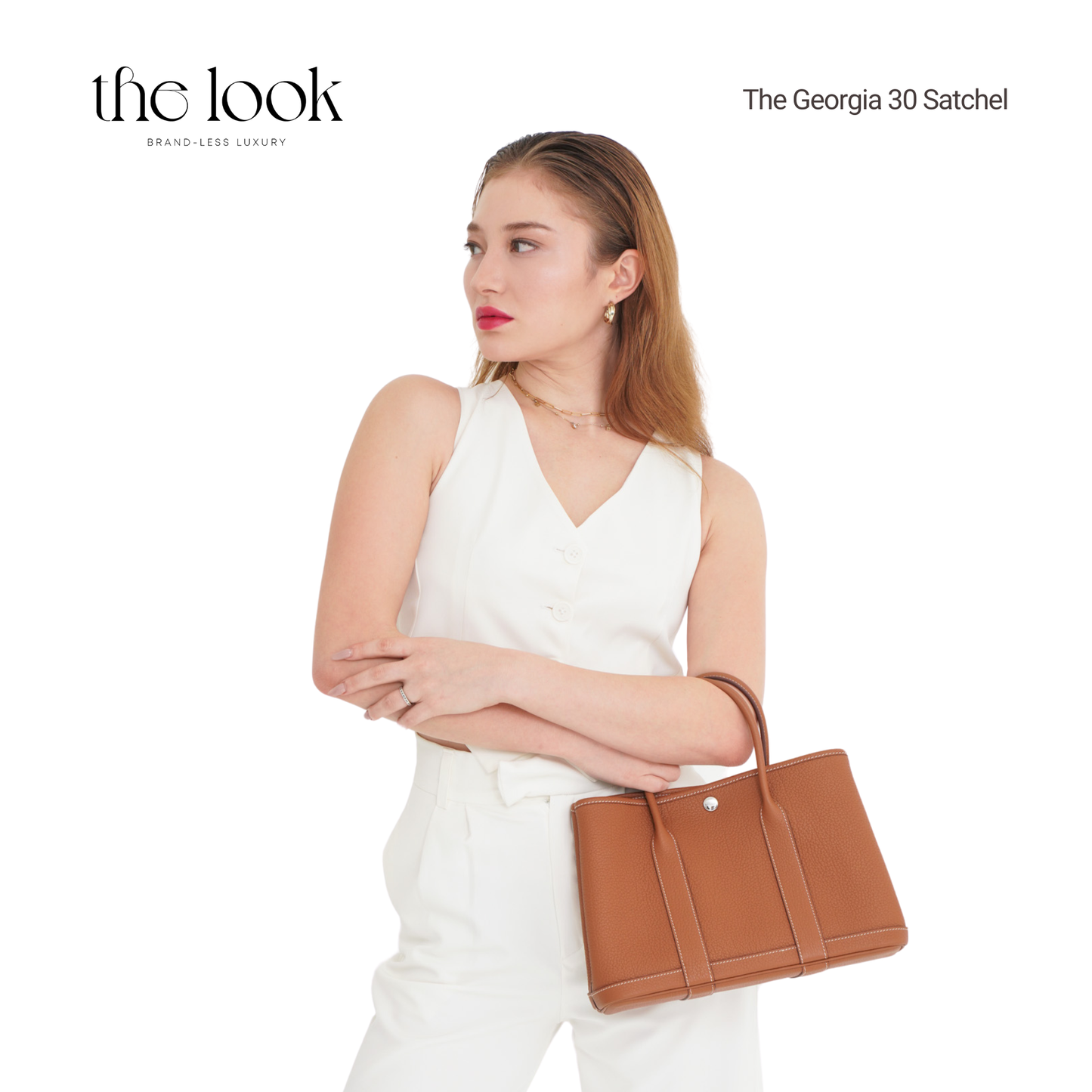 Woman holding a brown satchel with 'the look' branding on a white background | The Look Officiel