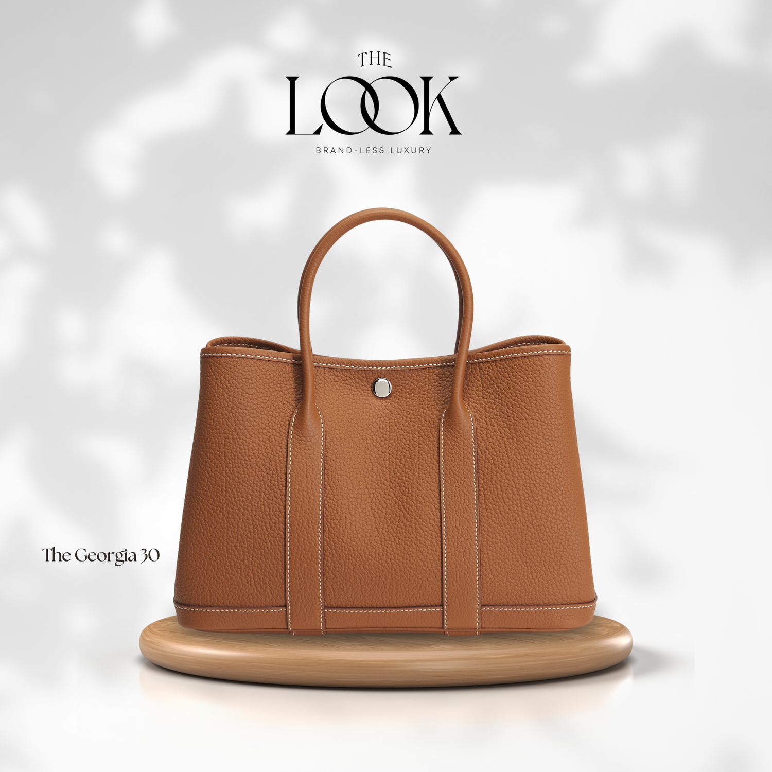 Brown leather handbag on a white platform with 'The Look' branding. | The Look Officiel