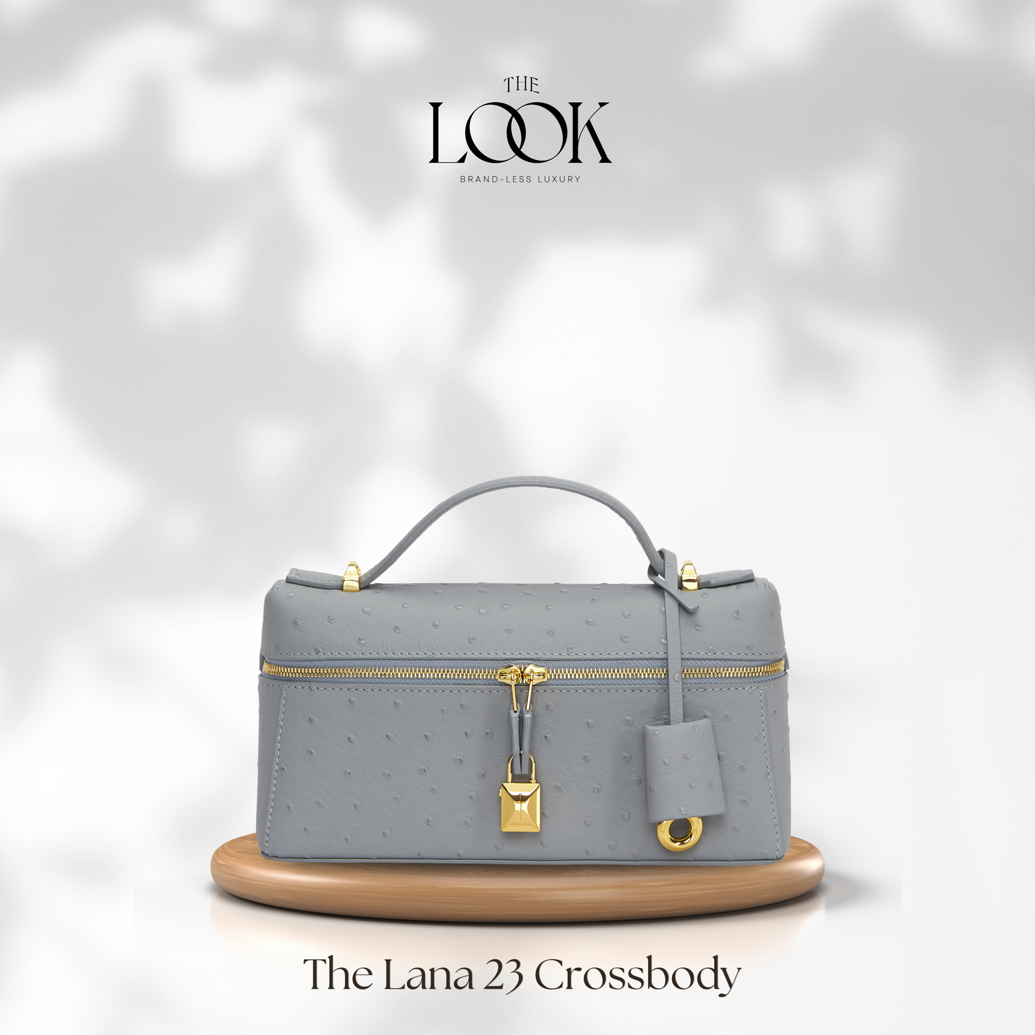 Gray crossbody bag with gold accents on a white background, featuring 'The Look' brand. | The Look Officiel