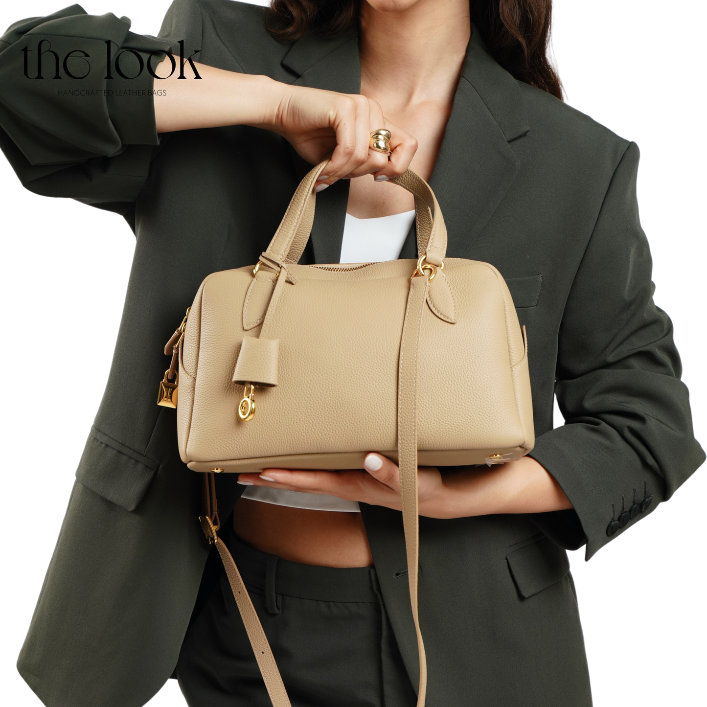 Person holding a beige handbag with a plain background. | The Look Officiel