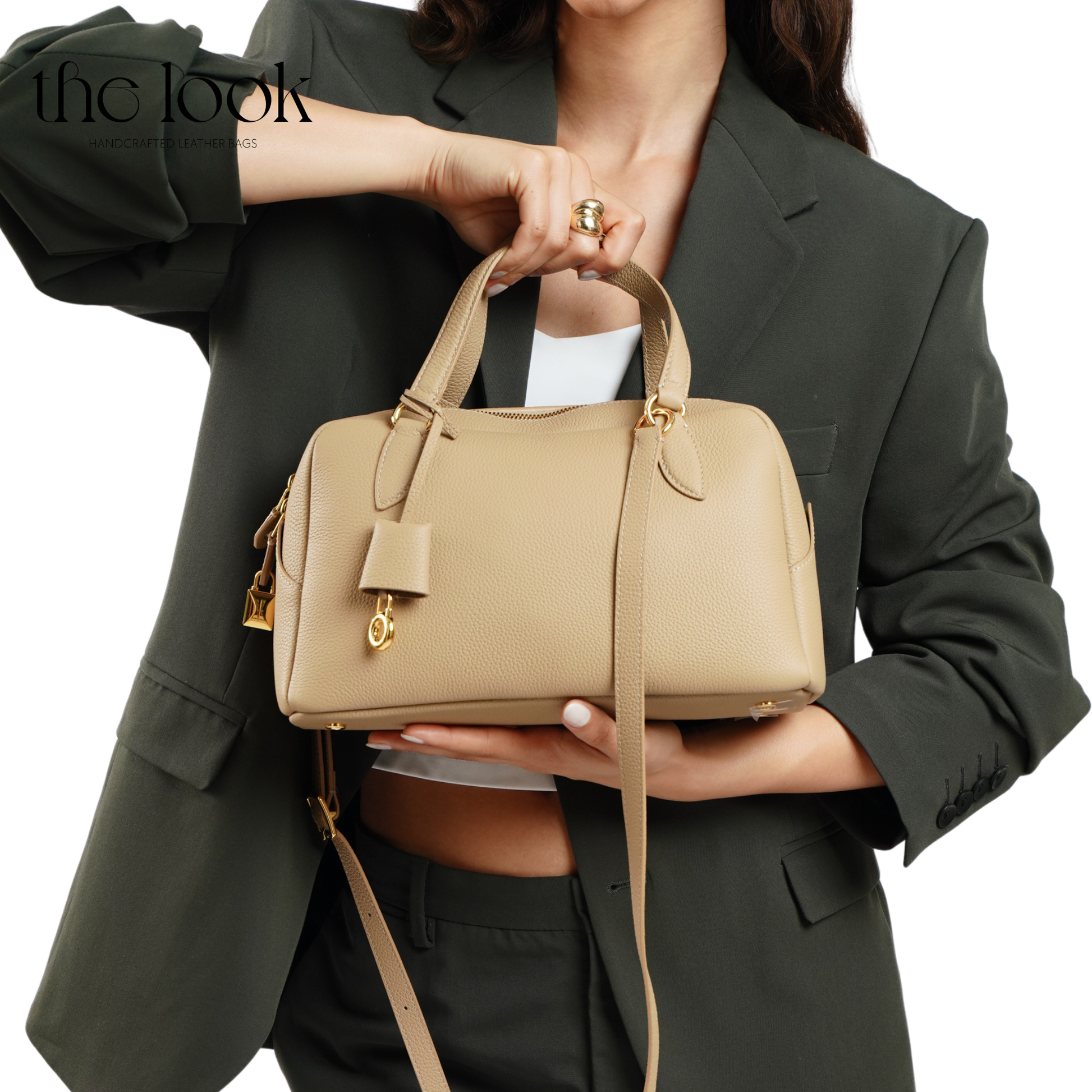 Person holding a beige handbag with a plain background. | The Look Officiel