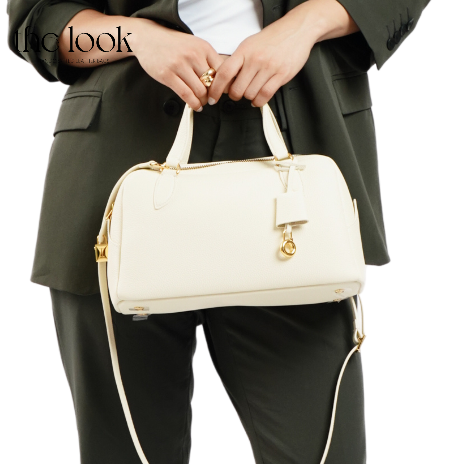 Person holding a cream handbag with gold accents on a white background. | The Look Officiel