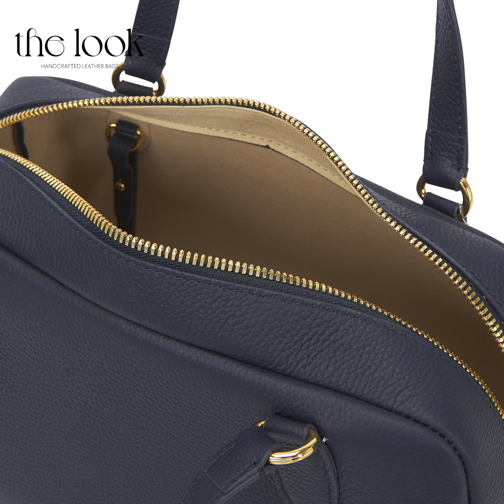 Navy blue handbag with gold zipper and trim on a white background. | The Look Officiel