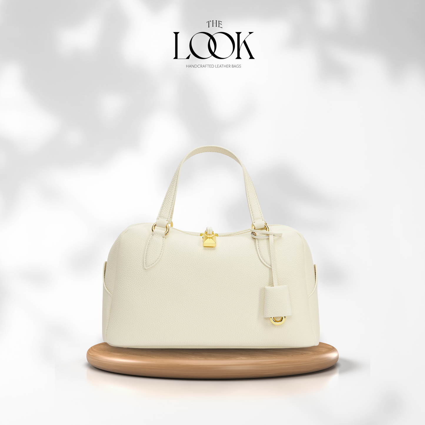 White handbag with gold accents on a wooden stand against a white background, featuring 'The Look' brand. | The Look Officiel