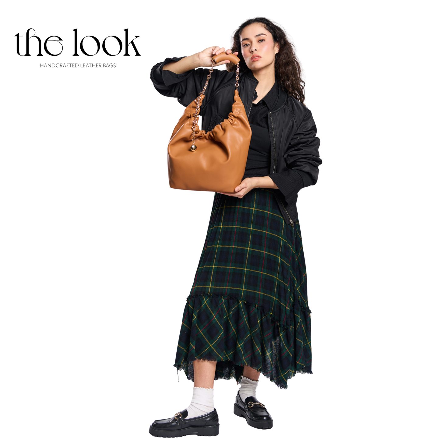 Woman holding a brown leather handbag with 'the look' branding on a white background. | The Look Officiel