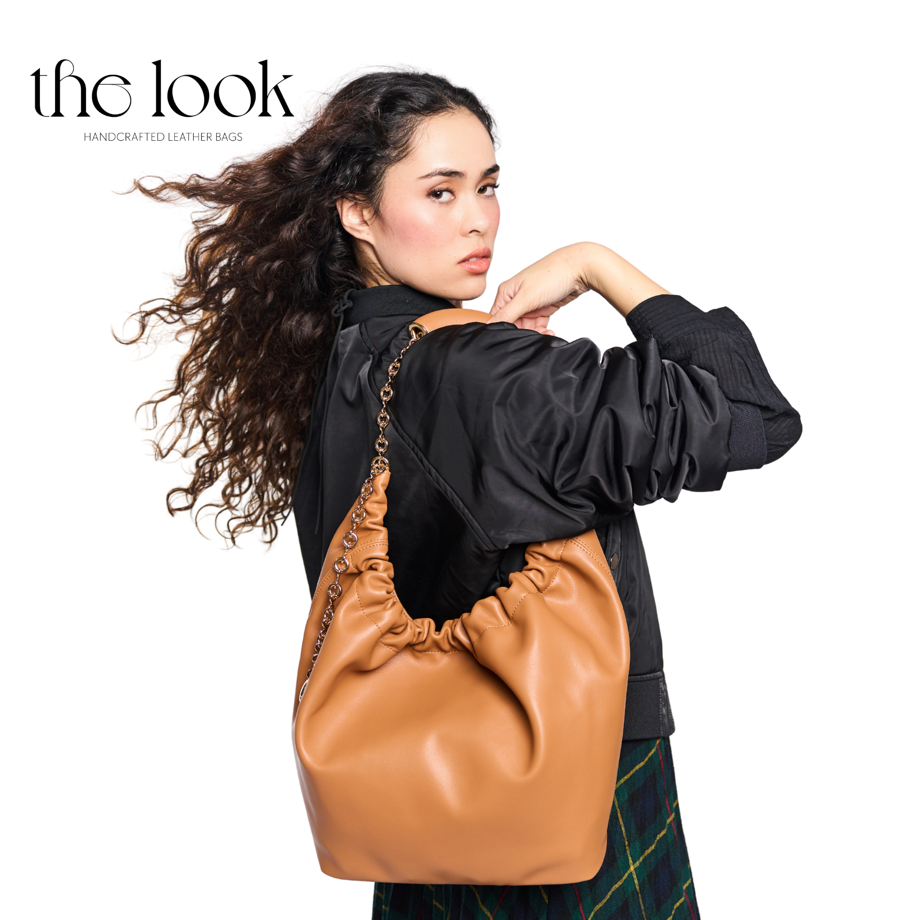Woman carrying a tan leather handbag with 'the look' branding. | The Look Officiel