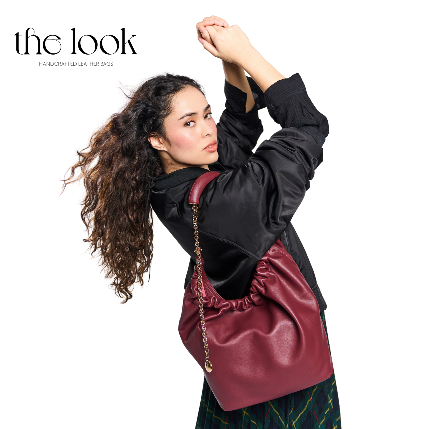 Woman holding a maroon leather bag with 'the look' branding on a white background | The Look Officiel