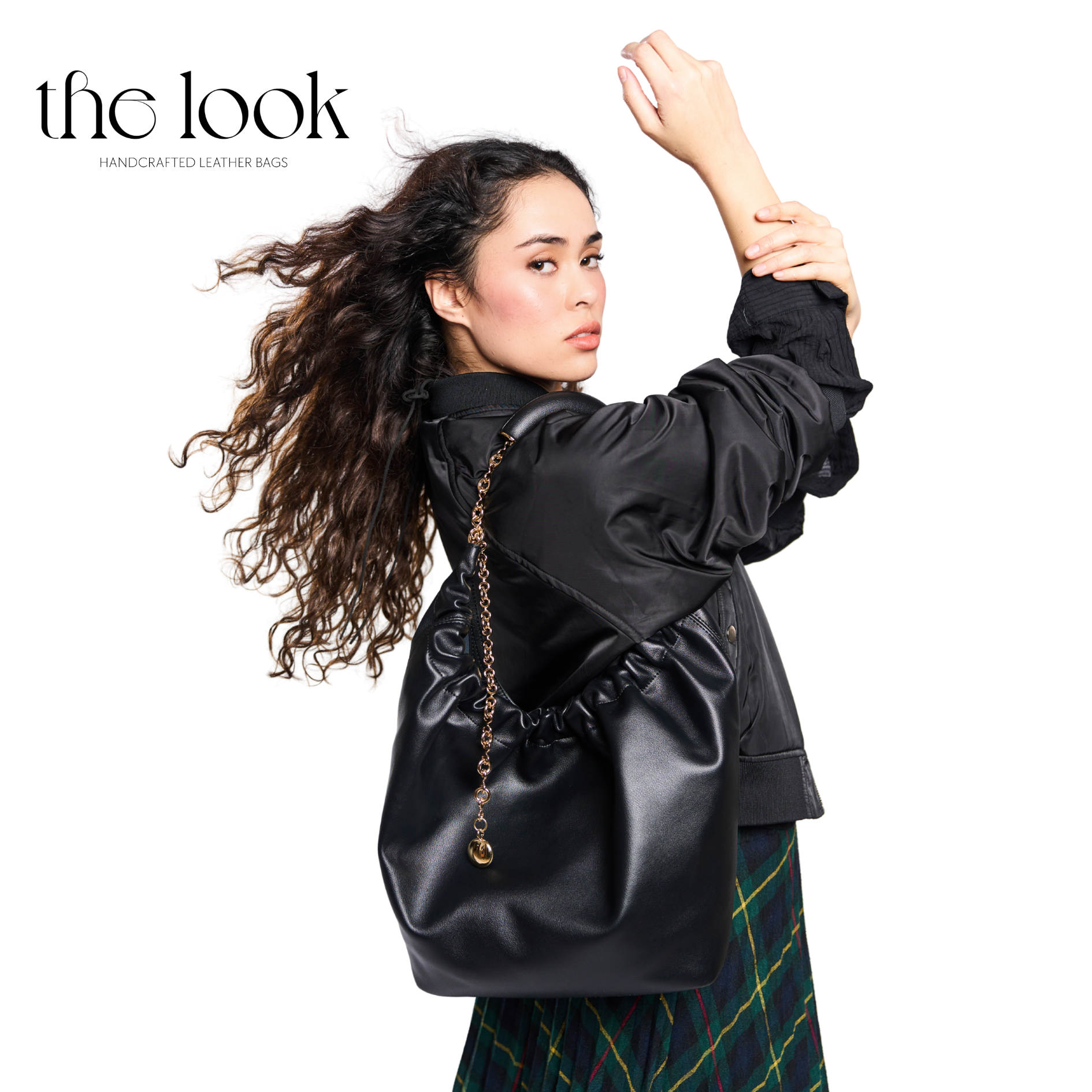 Woman wearing a black leather bag with 'the look' branding on a white background. | The Look Officiel