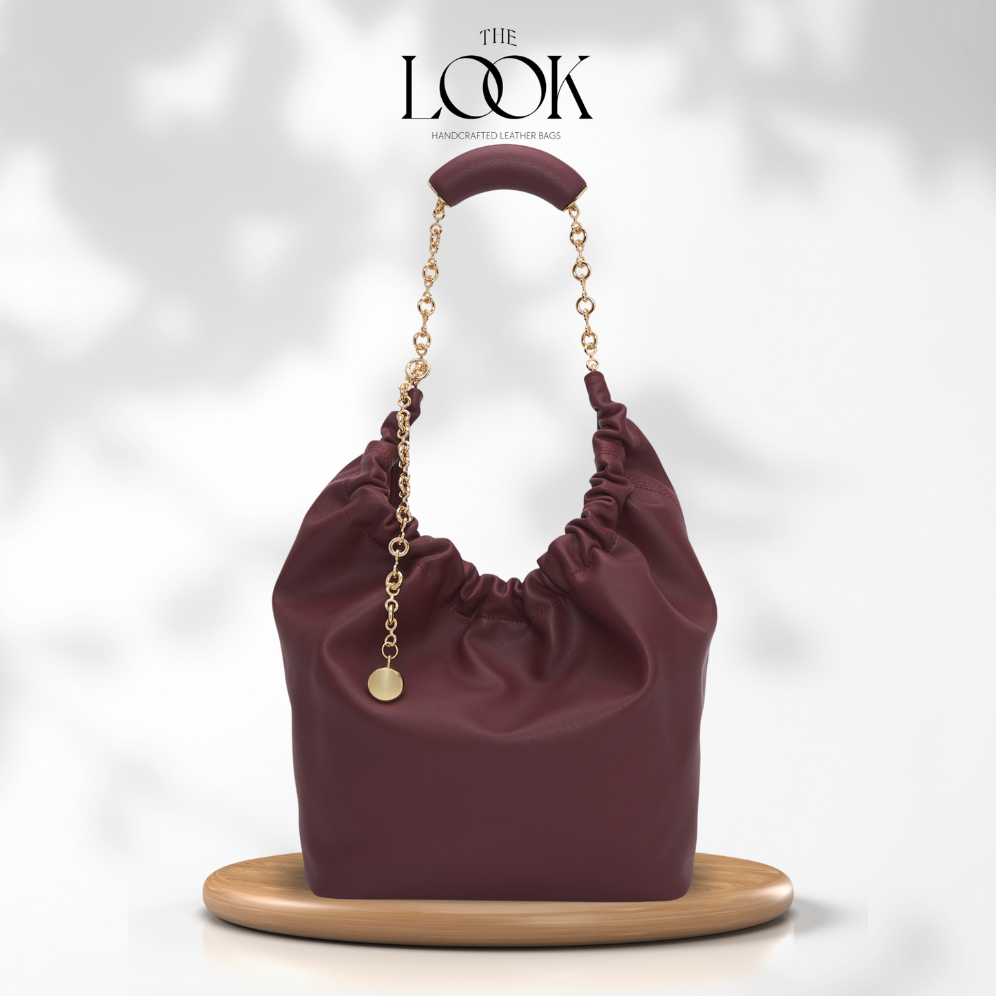 Maroon handbag with gold chain on a white background, branded 'The Look'. | The Look Officiel