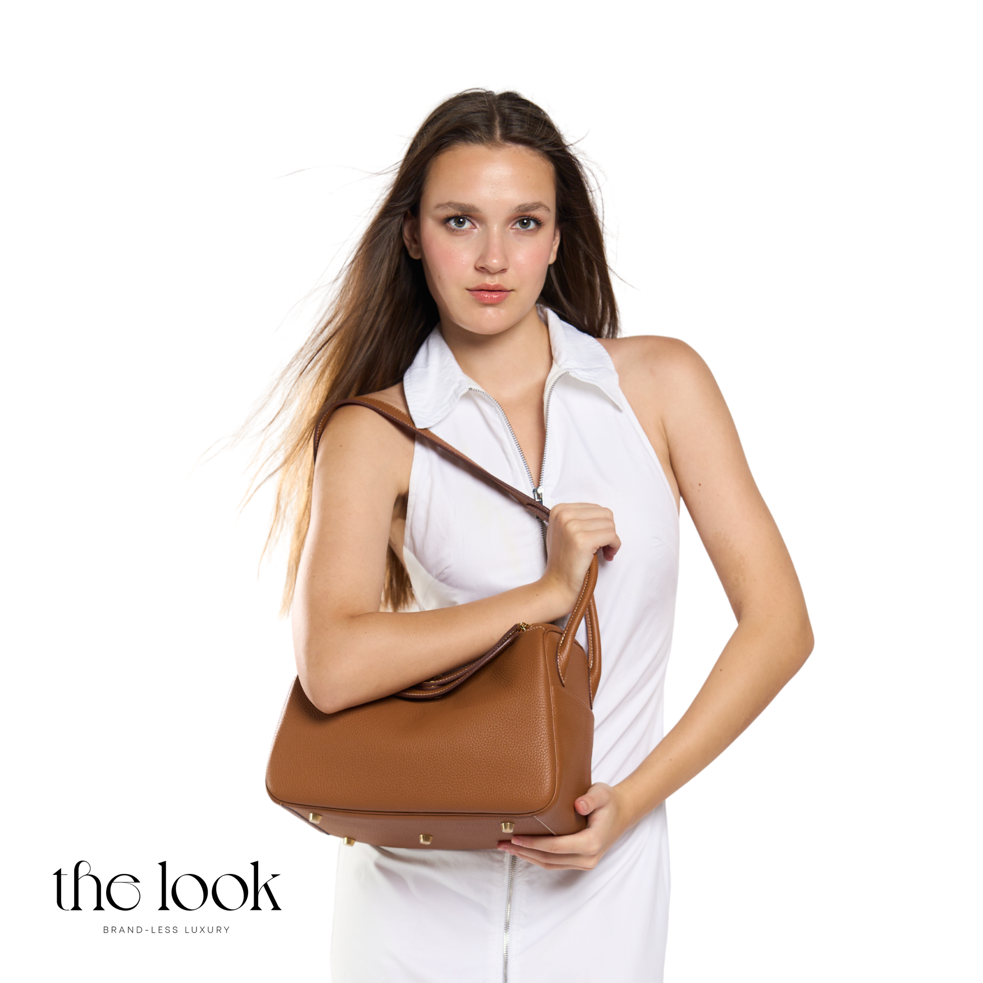 Woman holding a brown handbag against a white background with 'the look' branding. | The Look Officiel