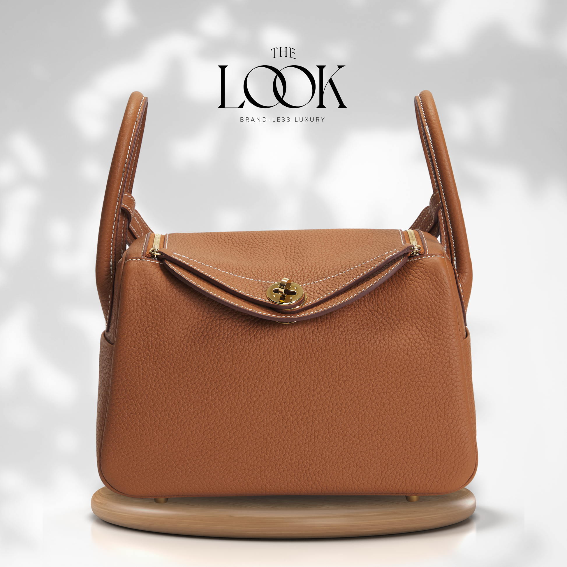 Brown leather handbag with gold clasp on a light gray background, featuring 'The Look' brand. | The Look Officiel