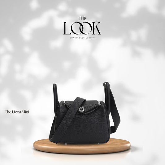 Black handbag on a wooden stand with 'The Look' branding on a light gray background | The Look Officiel