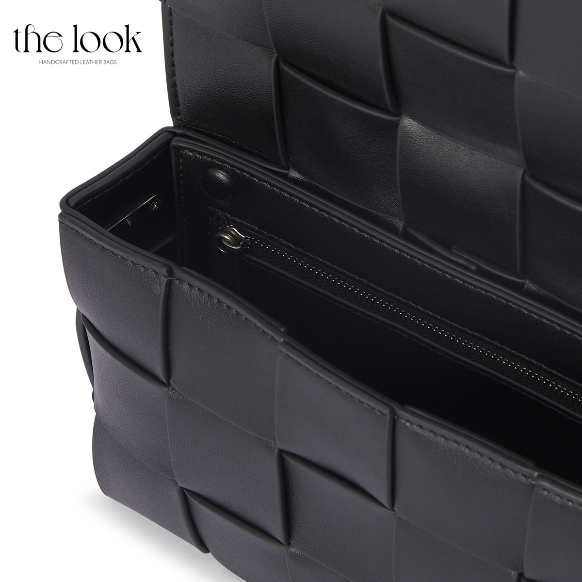 Close-up of black Loop Grid Extra leather bag interior with zippered pocket and woven flap | The Look Officiel
