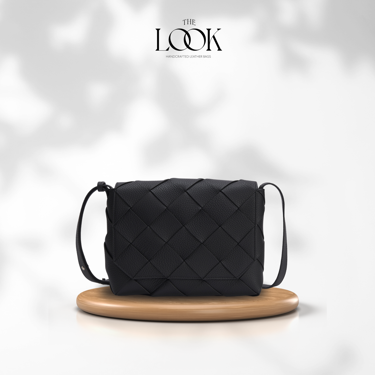 Black Loop Weave Crossbody bag with woven pebbled leather panels and adjustable strap on a wooden display | The Look Officiel