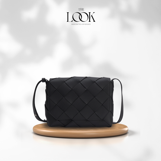 Black Loop Weave Crossbody bag with woven pebbled leather panels and adjustable strap on a wooden display | The Look Officiel