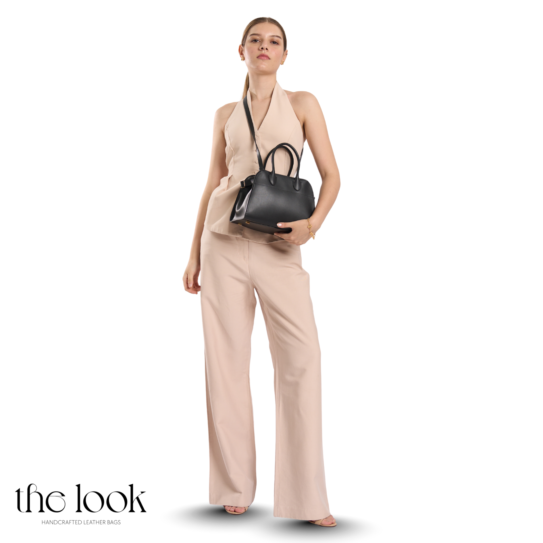 Woman holding a black handbag wearing a beige outfit with 'the look' branding. | The Look Officiel
