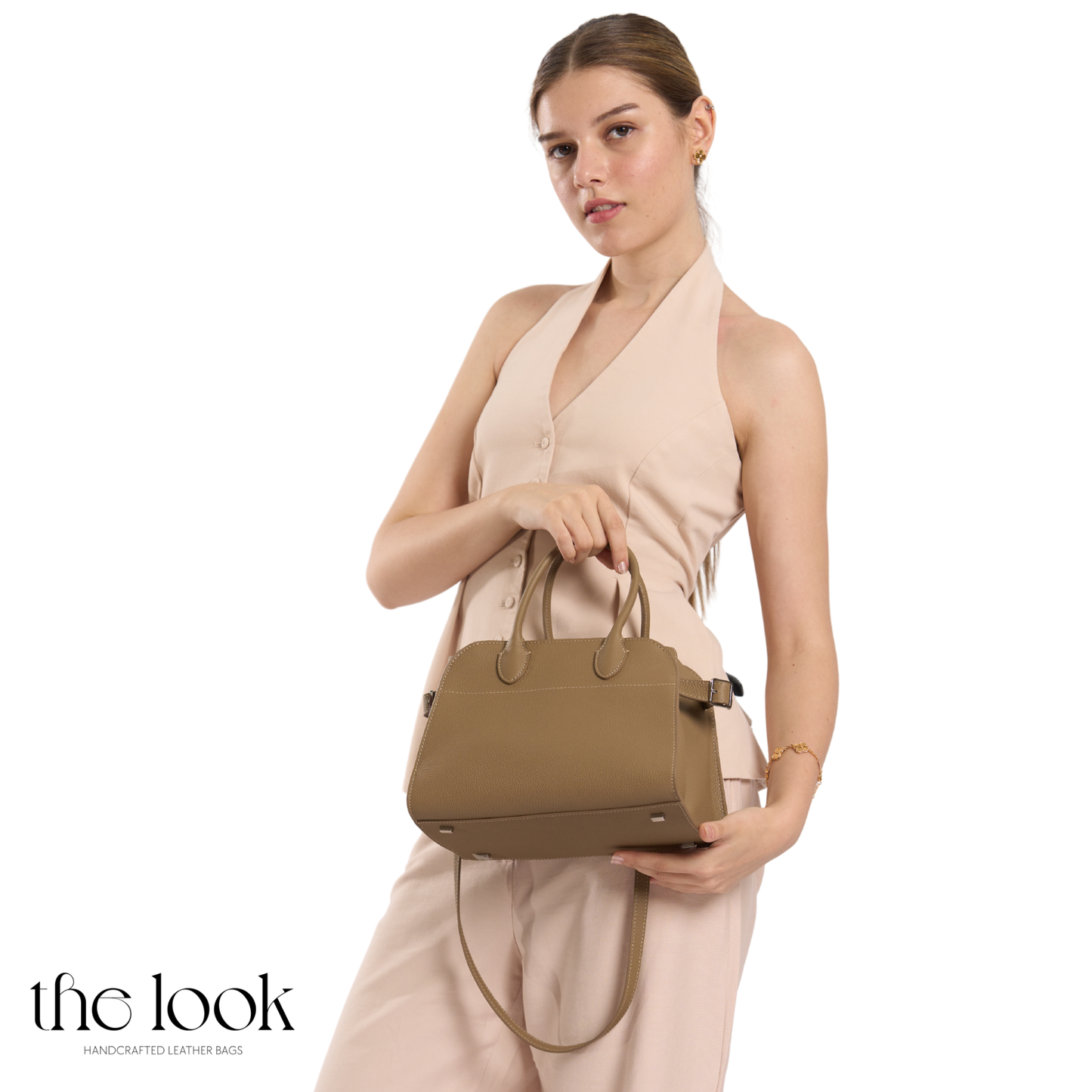 Woman holding a brown handbag against a white background with 'the look' branding. | The Look Officiel