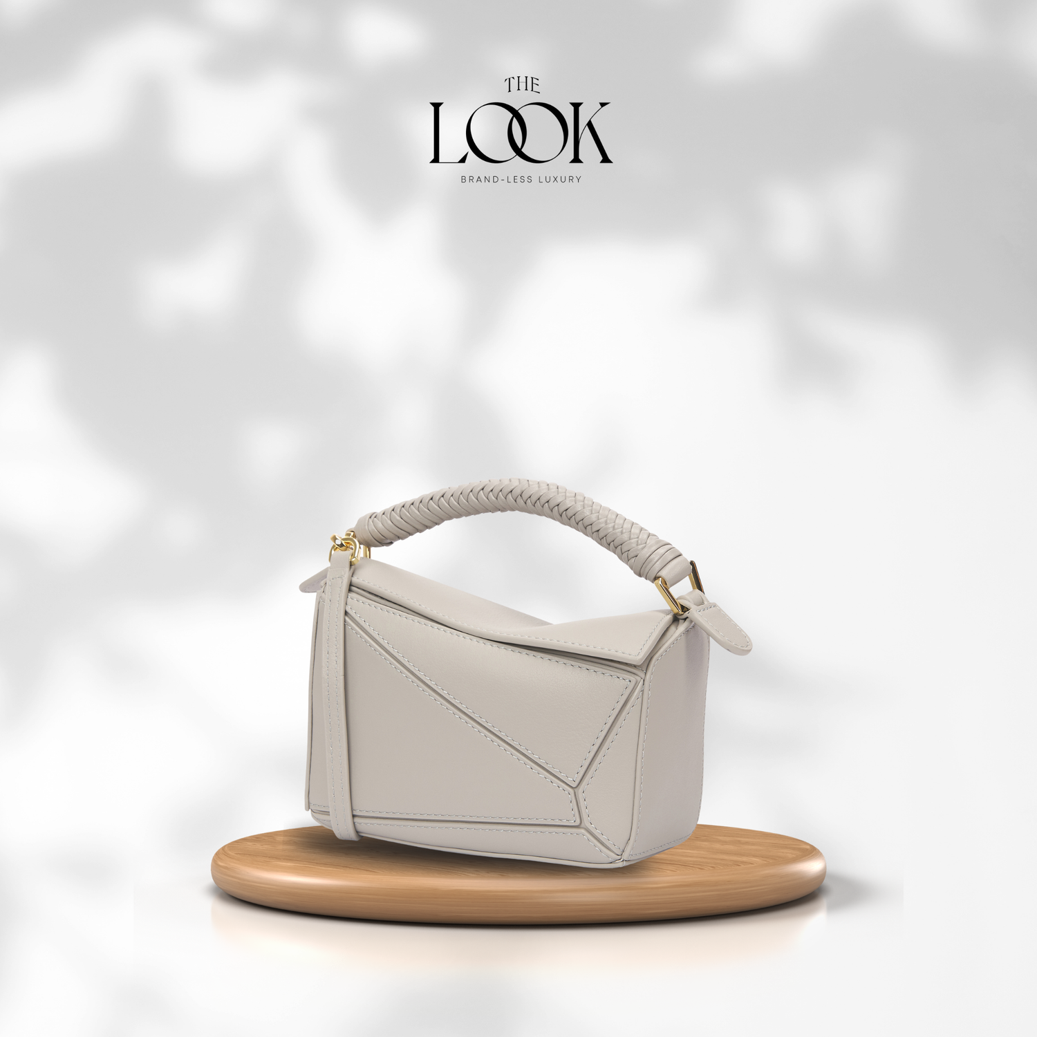 White handbag with a gold handle on a wooden stand against a soft white background, featuring 'The Look' brand. | The Look Officiel