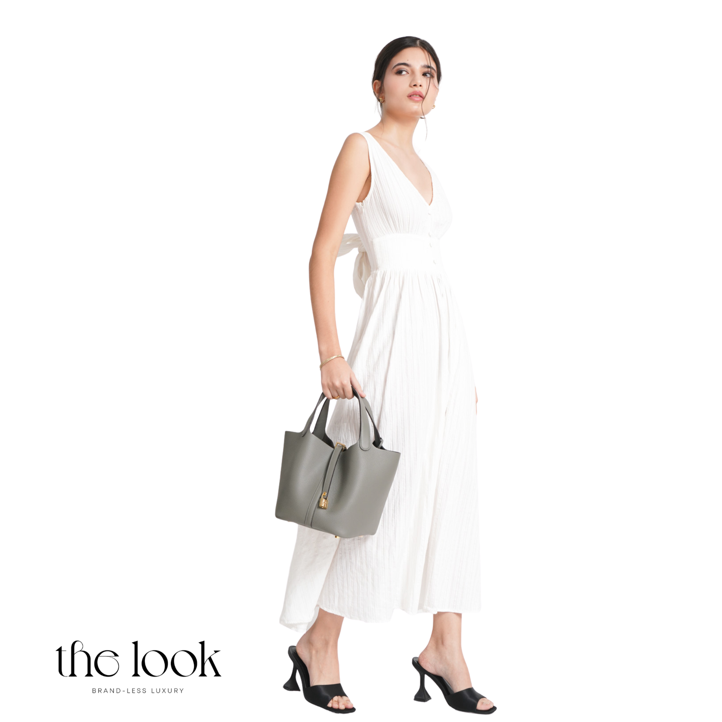 Woman in a white dress holding a gray handbag on a white background with 'the look' branding. | The Look Officiel
