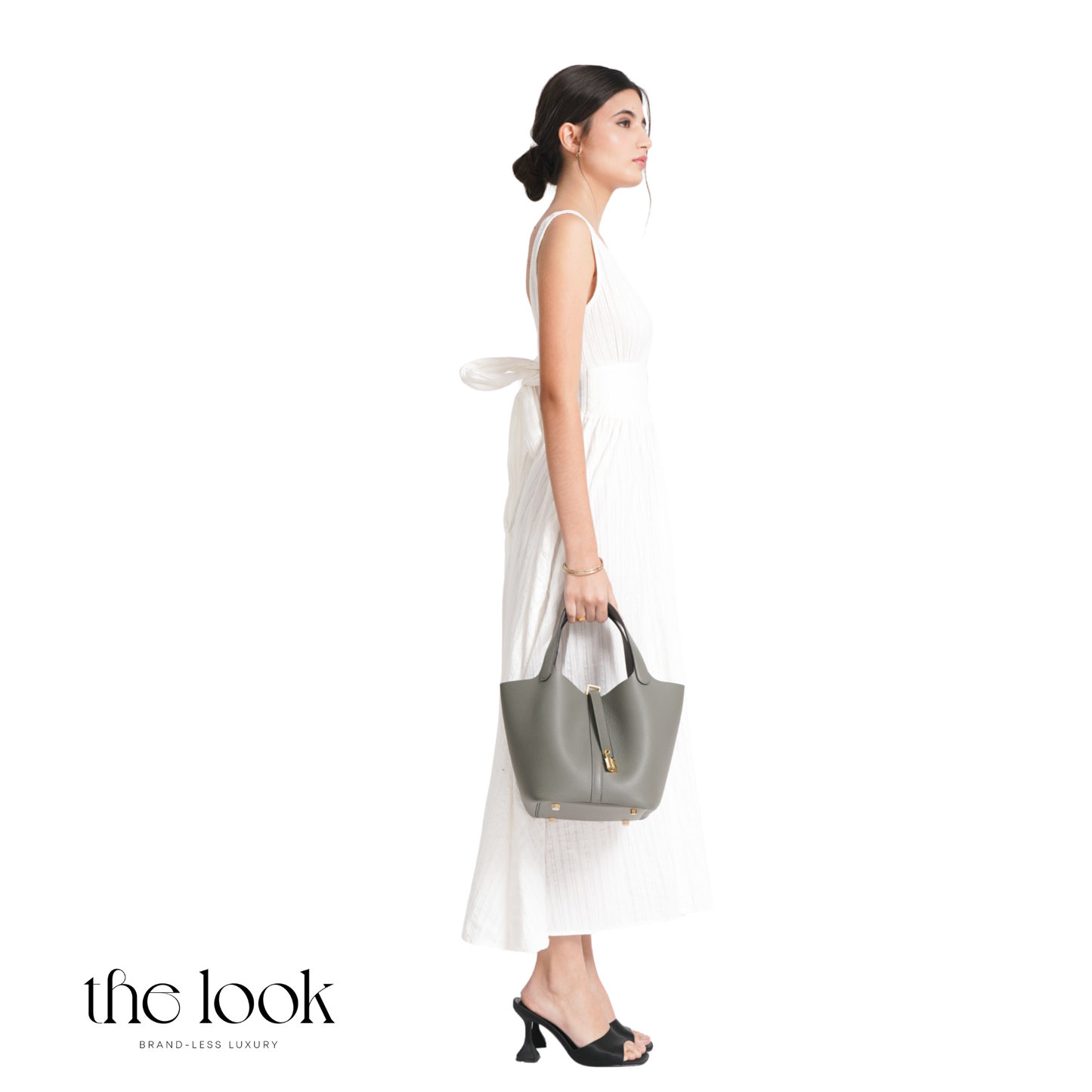 Woman holding a gray handbag against a white background with 'the look' branding. | The Look Officiel