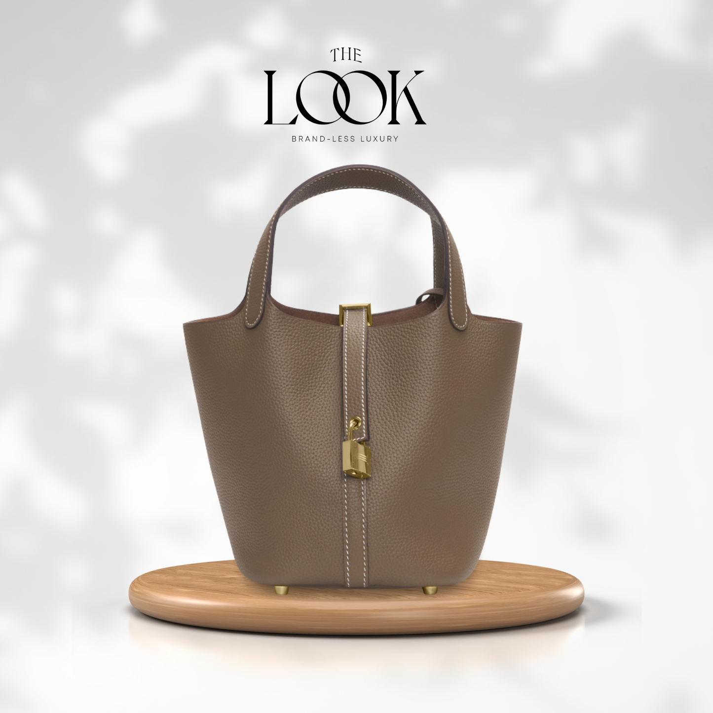 Brown handbag with gold accents on a wooden stand against a light gray background, featuring 'The Look' brand. | The Look Officiel