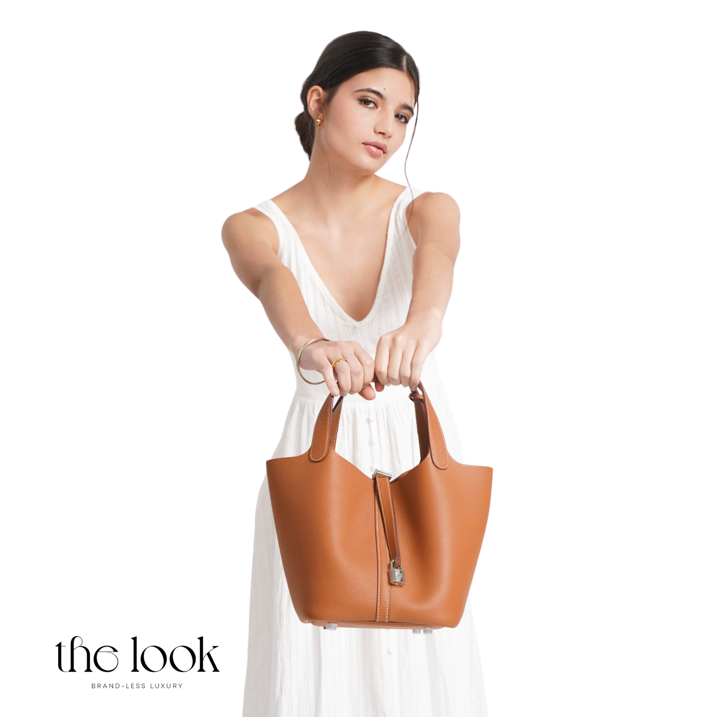 Woman holding a brown leather handbag against a white background with 'the look' branding. | The Look Officiel