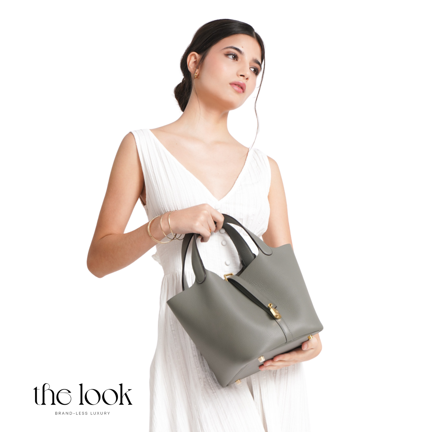 Woman holding a gray handbag against a white background with 'the look' branding. | The Look Officiel
