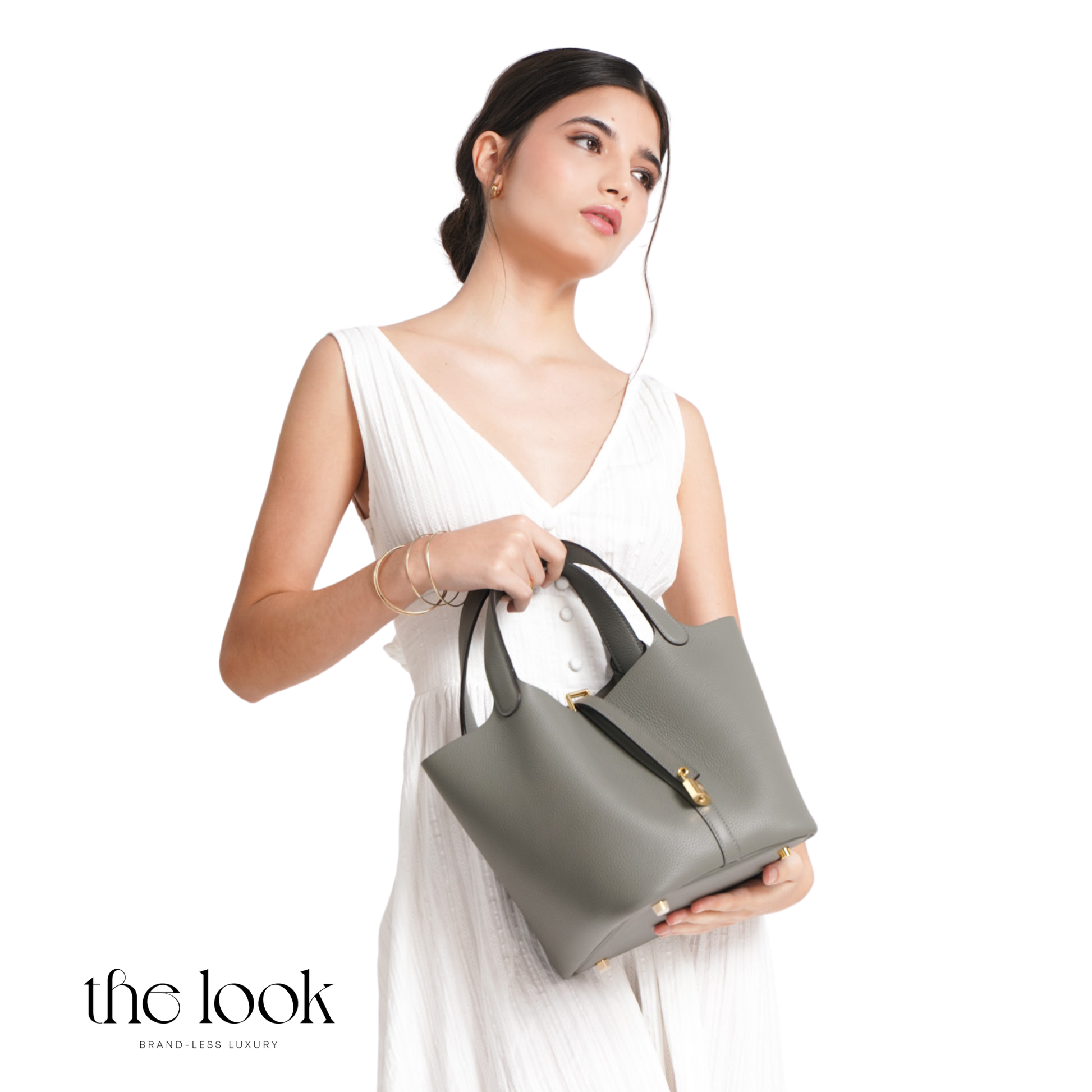 Woman holding a gray handbag against a white background with 'the look' branding. | The Look Officiel