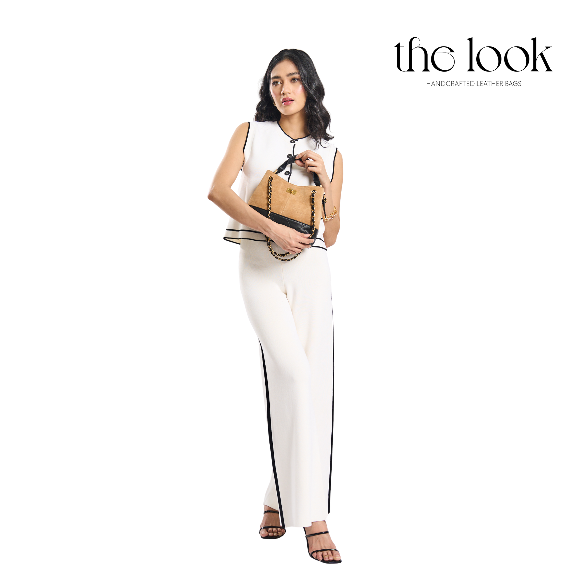 Woman holding a handbag with 'the look' brand on a white background. | The Look Officiel