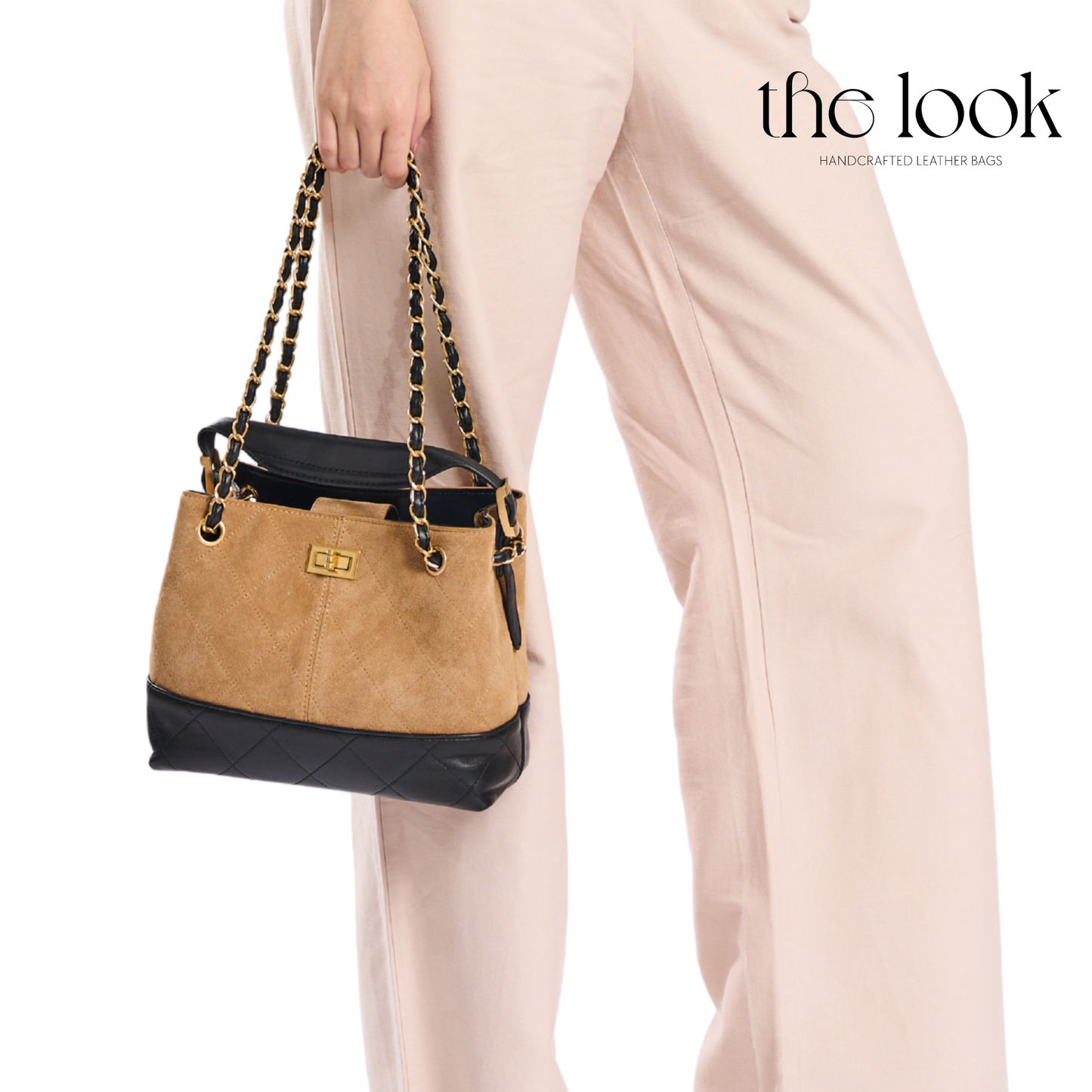 Tan and black handbag with gold chain handle held by a person wearing light pink pants, branded 'the look'. | The Look Officiel
