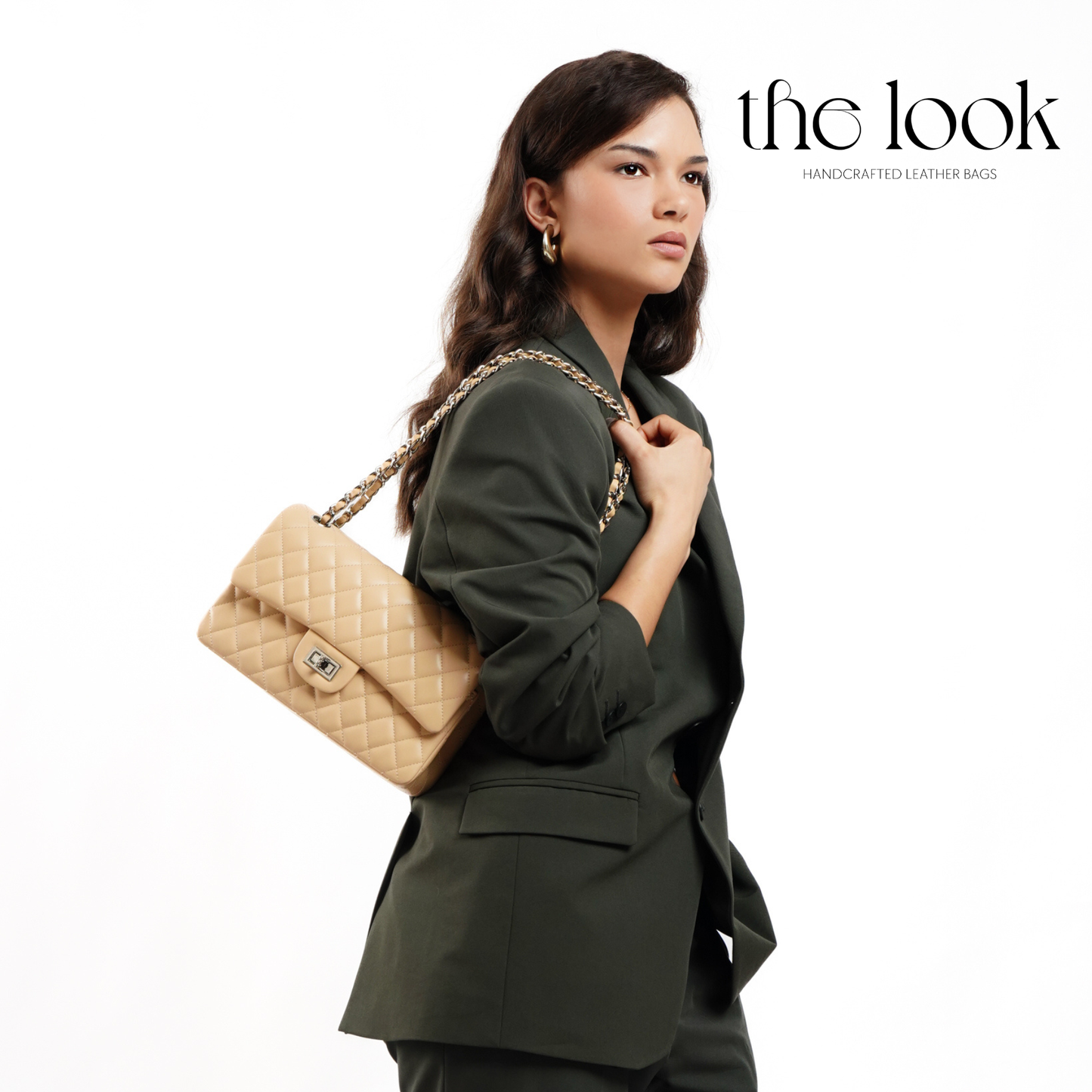 Woman in a green suit holding a beige quilted handbag with 'the look' branding. | The Look Officiel