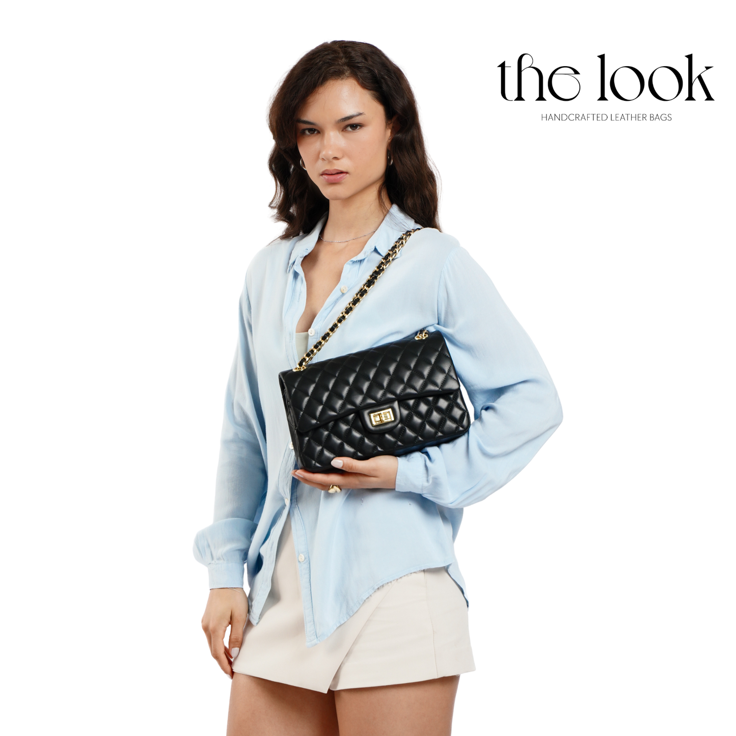 Woman holding a black quilted handbag with 'the look' branding. | The Look Officiel