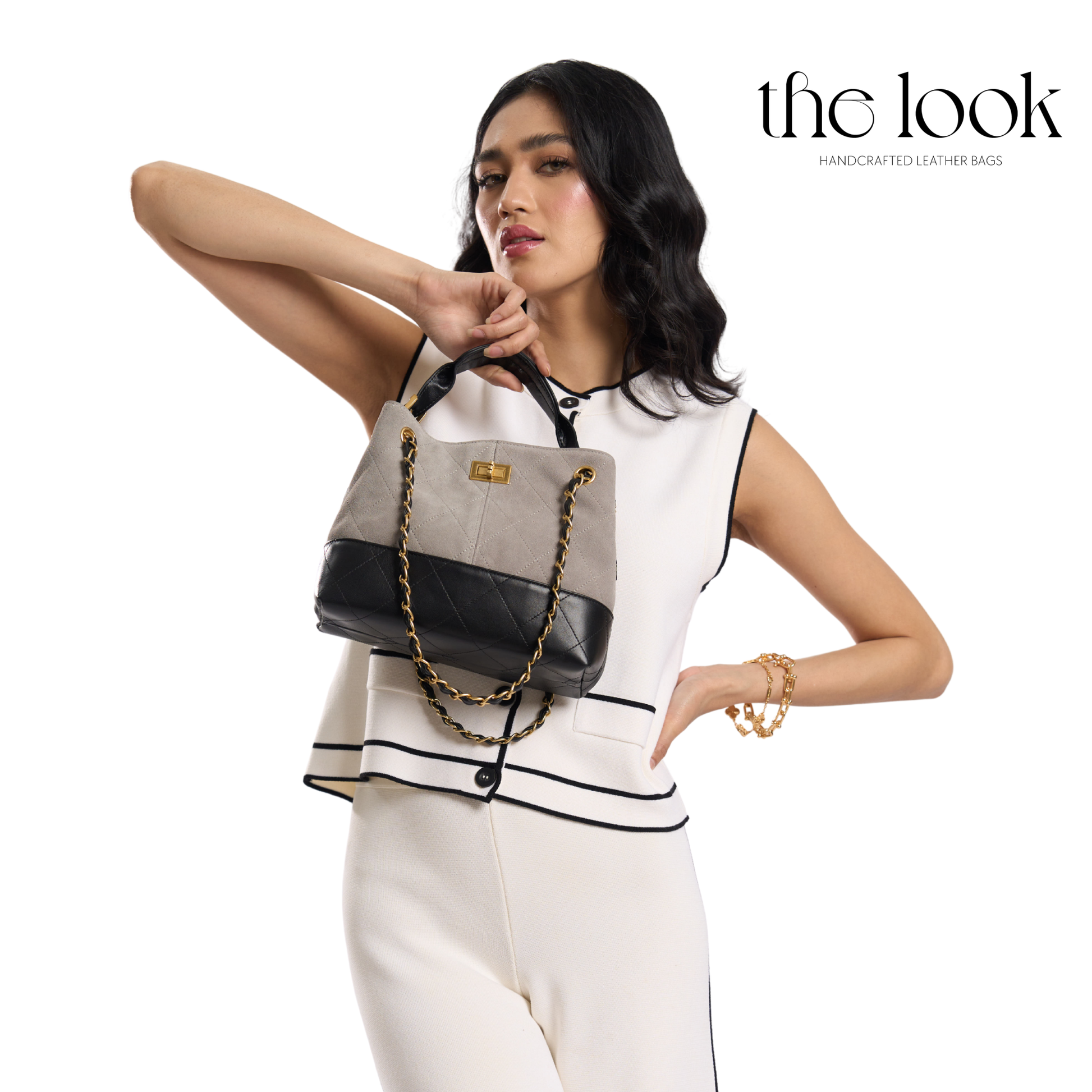 Woman holding a gray and black handbag with 'the look' branding. | The Look Officiel