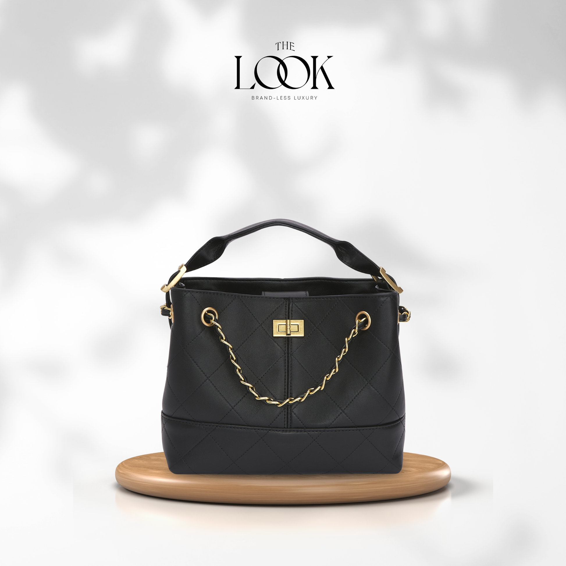 Black handbag with gold chain detail on a white background, featuring 'The Look' brand. | The Look Officiel